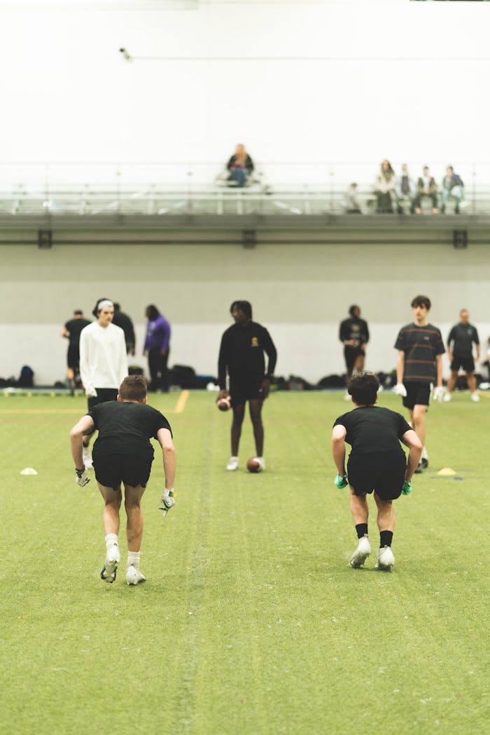Teenage boys practicing football indoors, focusing on drills and skill development.